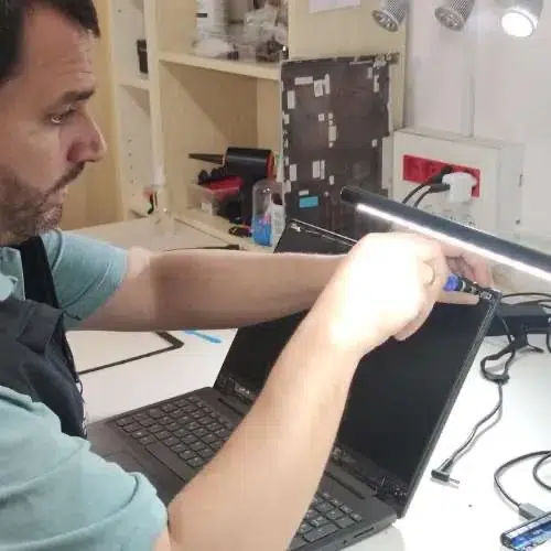 Técnico desmontando el marco de la pantalla de un portátil en el taller de Barcelona